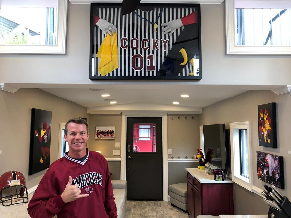 Garrett Humphries poses in front of part of his framed Cocky suit from his days as the Carolina mascot