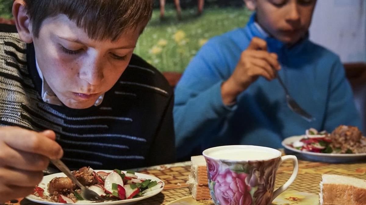 In this photo taken on Tuesday, April 5, 2016, Viktoria Vetrov's sons Bogdan, left, and Kolya, eat at home in Zalishany, 53 km (32 miles) southwest of the destroyed reactor of the Chernobyl plant, Ukraine. Viktoria Vetrov, a 37-year-old housewife, keeps two cows in order to help feed her four children. One of her children, eight-year-old Bogdan suffers from an enlarged thyroid. Vetrov suspects it’s caused by contaminated food.