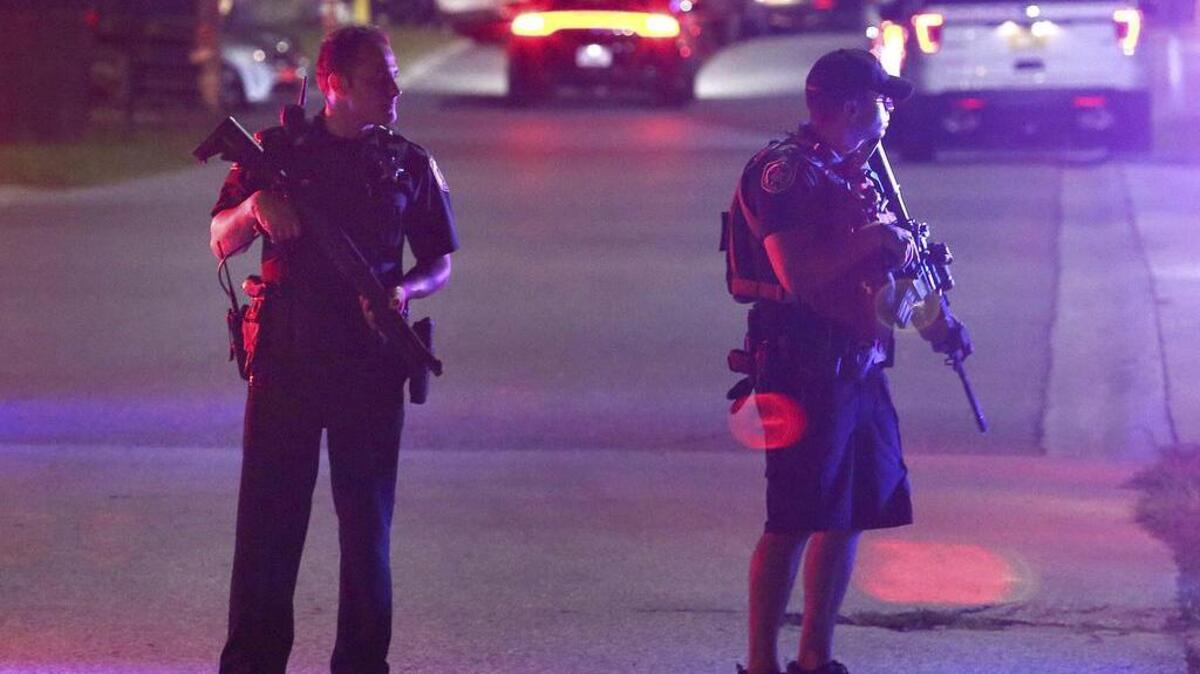 Two law enforcement officers stand guard outside Osceola Regional Medical Center in Kissimmee after two Kissimmee police officers were shot Friday, Aug. 18, 2017, in Kissimmee, Fla. One police officer was shot and killed and another gravely injured by gunfire while checking suspicious people in the central Florida city of Kissimmee, police said early Saturday.