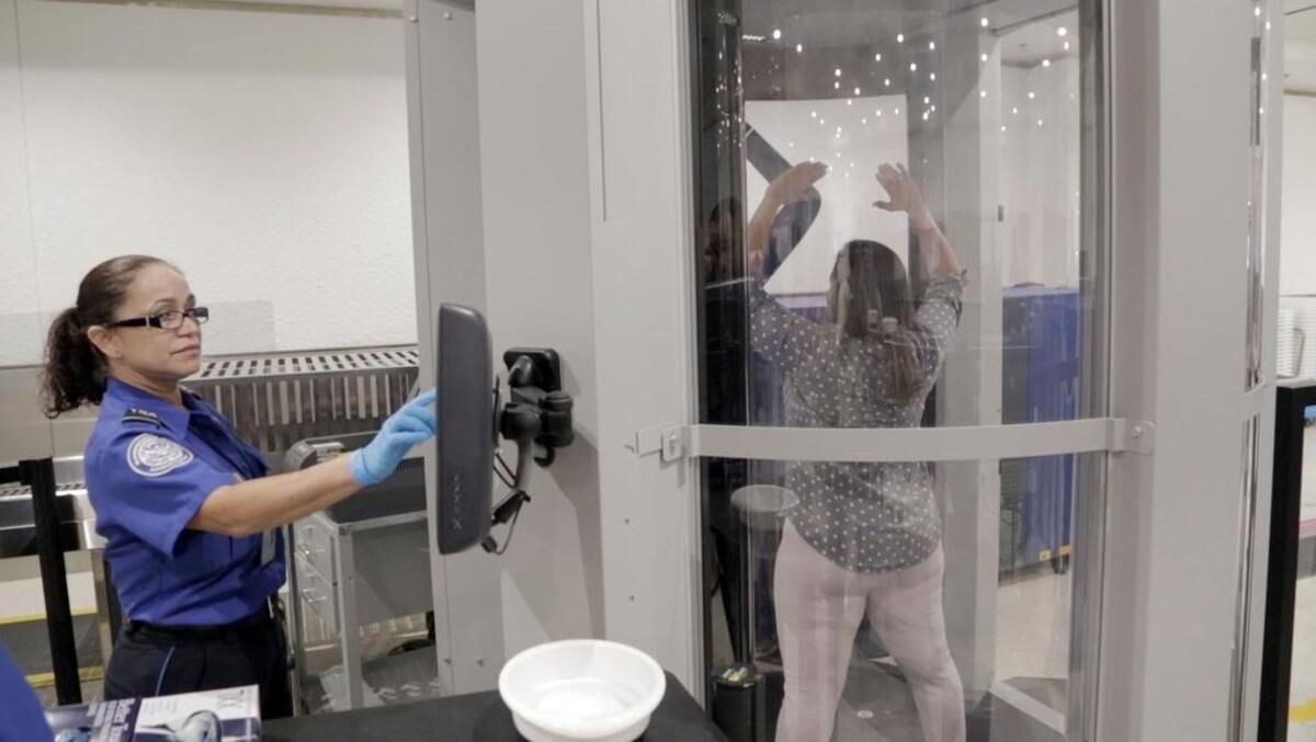 A TSA agent, prepares to scan a passenger in Miami in July in the Advanced Imaging Technology (AIT) units which have automated target recognition software, designed to ensure privacy while facilitating a streamlined checkpoint screening process. This means that the system generates the same generic image for all passengers. The only difference is if a passenger has a possible threat on their person, a yellow box will appear on the screen and show the TSA officer where further screening will be necessary.