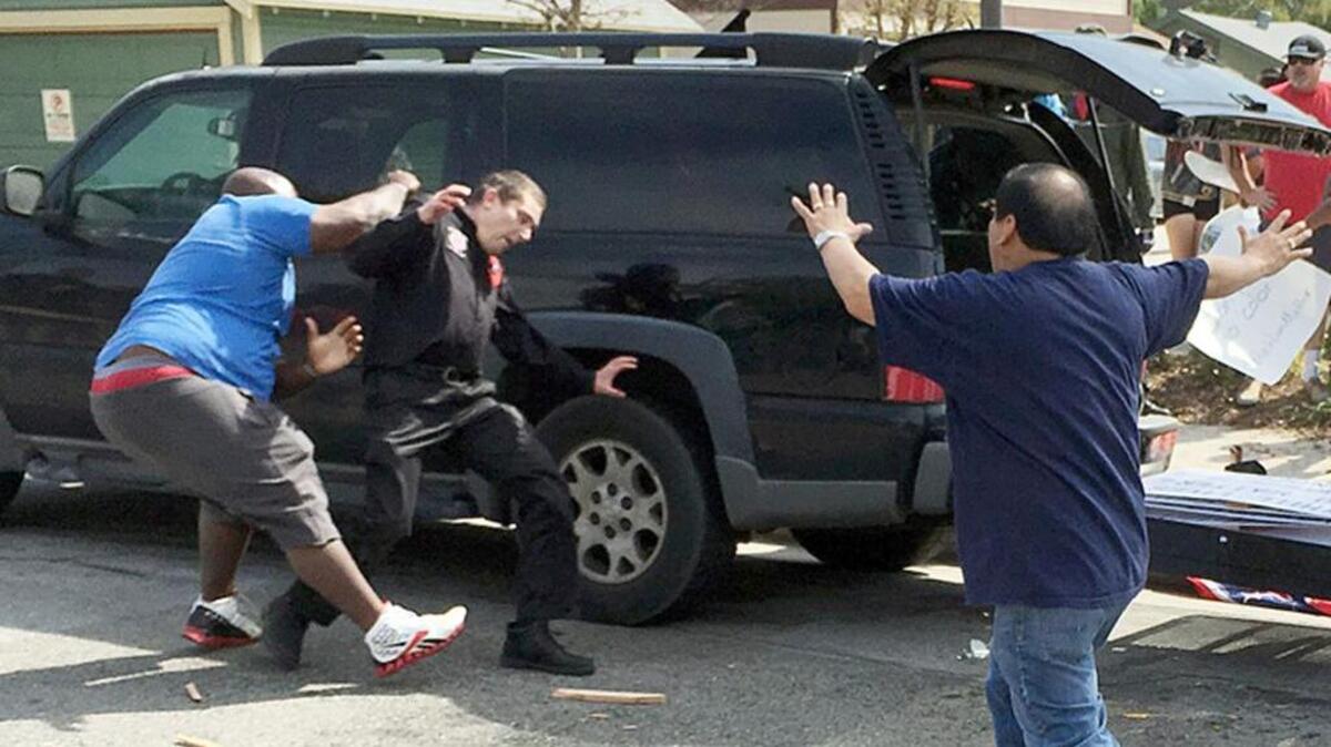 In this Feb. 27, 2016 photo provided by the B. Levin Center for the Study of Hate & Extremism, a man dressed in Ku Klux Klan garb, center, and a counter-protester, left, confront each other during a KKK rally at Pearson Park in Anaheim, Calif. This city is home to Disneyland, the self-proclaimed Happiest Place on Earth. It's also the place where the City Council once had a majority of Ku Klux Klan members and a Klanrally in a city park attracted 10,000 people. The KKK returned to that park Saturday, and violence ensued.