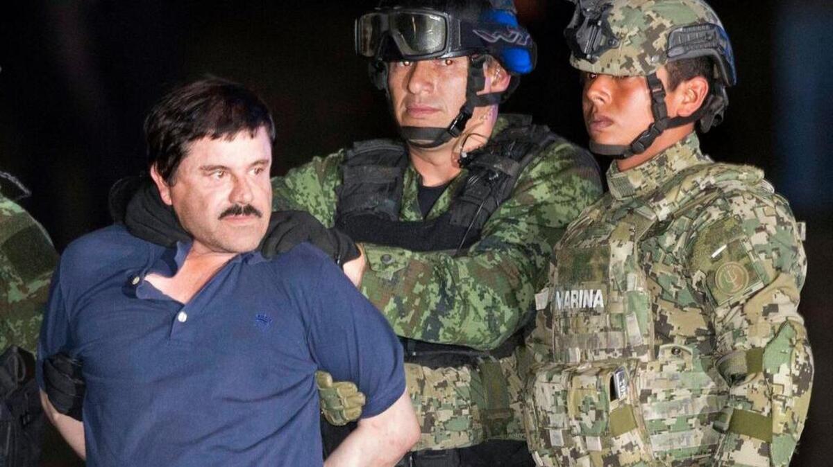 In this Friday, Jan. 8, 2016 photo, Joaquin "El Chapo" Guzman is made to face the press as he's escorted to a helicopter in handcuffs by soldiers and marines at a federal hangar in Mexico City. Guzman's second prison escape in 2015 from a top security prison though a tunnel had embarrassed President Enrique Pena Nieto and made his capture a national priority.