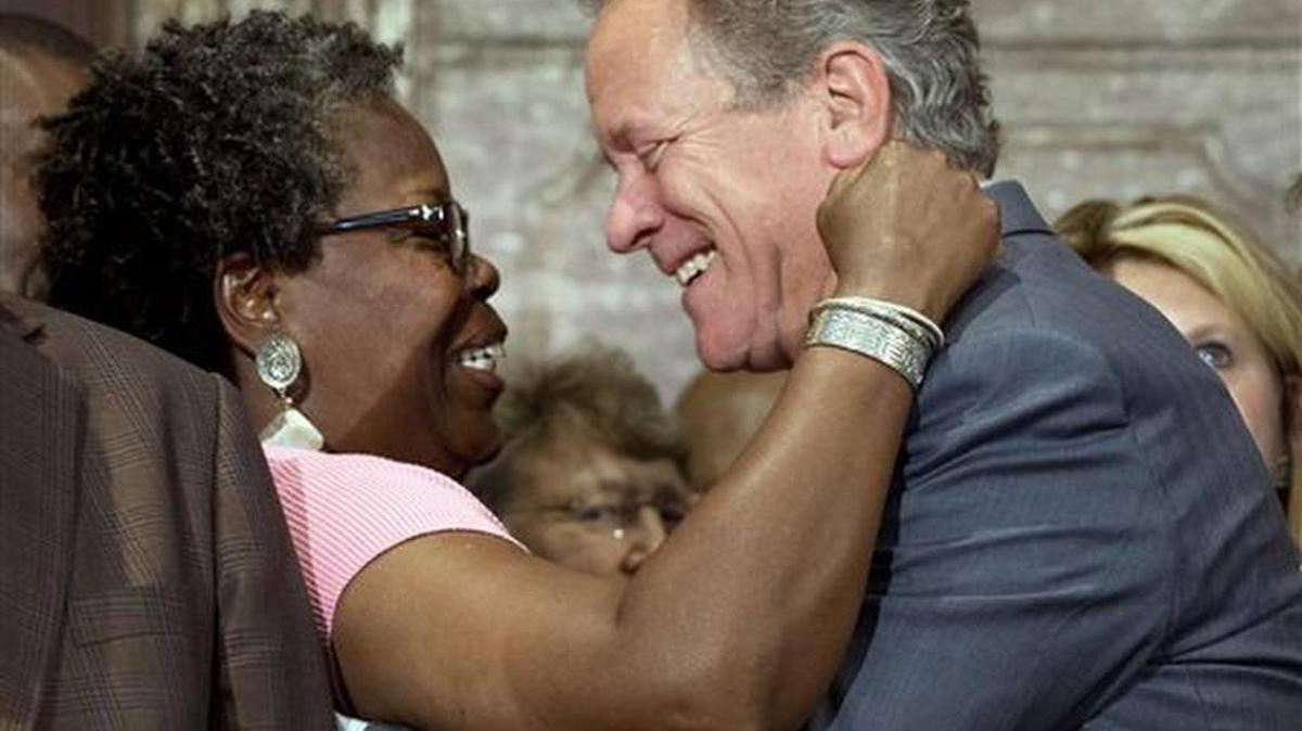 Rep. Gilda Cobb-Hunter, D-Orangeburg, left, reacts with former South Carolina Gov. David Beasley after a ceremony where Gov. Nikki Haley signed a bill into law, Thursday, July 9, 2015, at the Statehouse in Columbia, S.C.