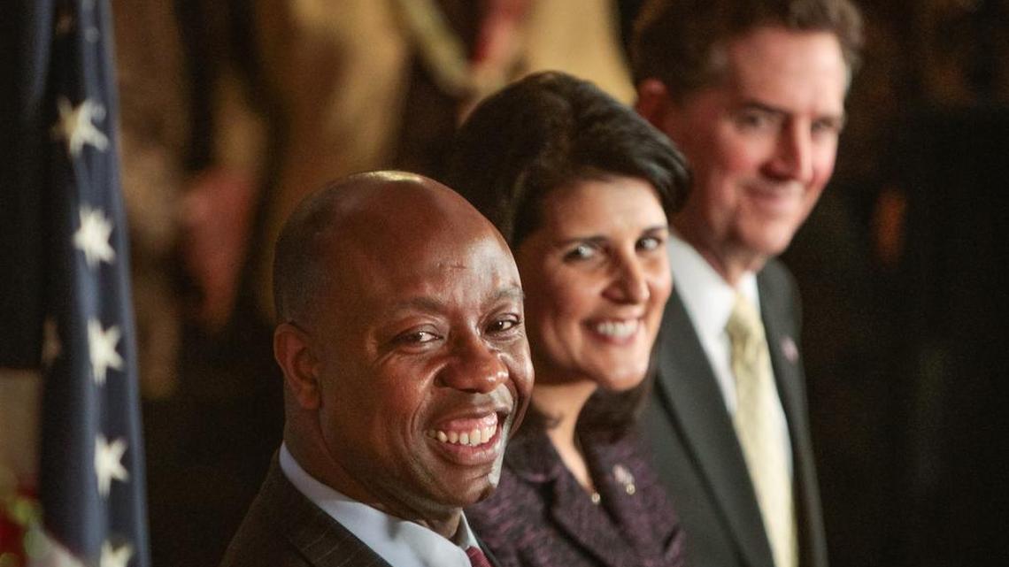 U.S. Rep. Tim Scott smiles as he listens to U.S. Senator Lindsey Graham after being officially introduced by Gov. Nikki Haley. center, to fill the vacant U.S.. Senate seat vacated by departing U. S. Sen. Jim DeMint, far right.