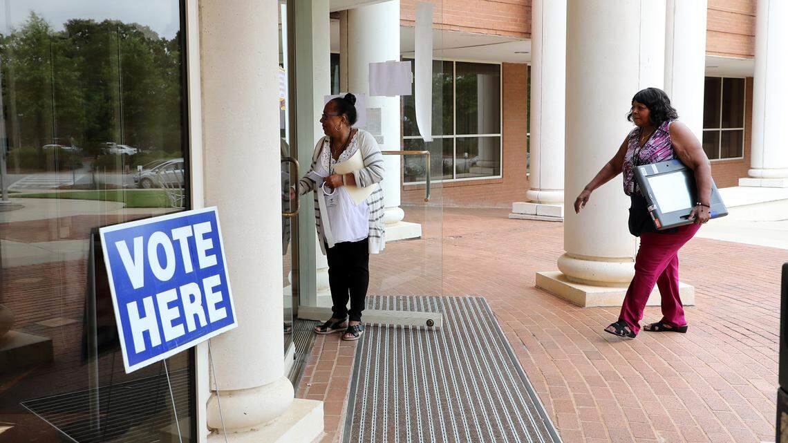 Poll workers Gloria Finch, left, and Barbara Ervin walk into Rock Hill City Hall with a voting machine Tuesday after assisting a physially challenged voter in a car with curbside voting.