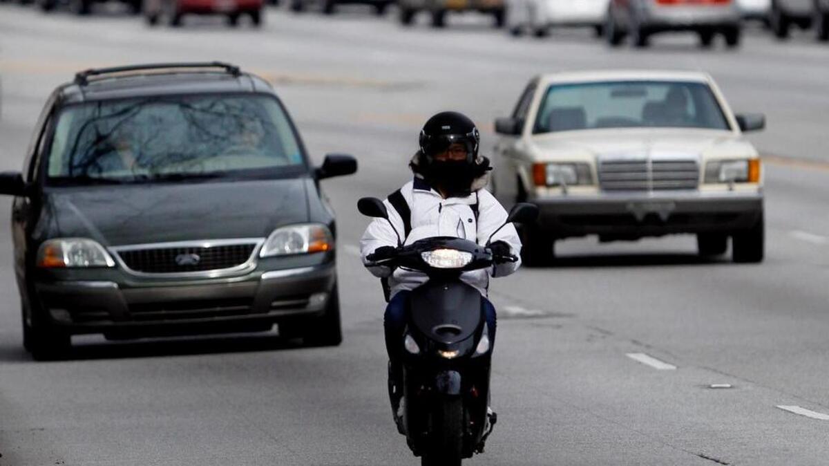A moped driver makes their way up Devine Street.