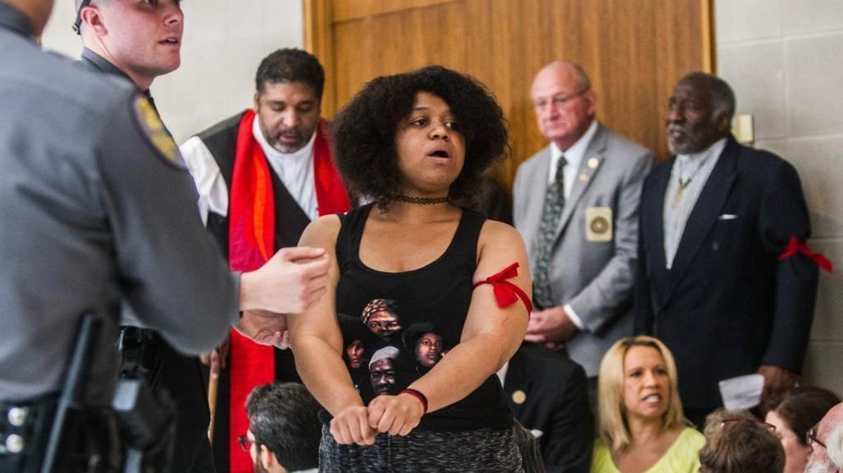 Rebekah Barber, the daughter of Rev. William Barber II, holds her wrists out while being arrested Tuesday, May 30, 2017 at the NC Legislative building. Thirty-two people were arrested for second-degree trespassing according to General Assembly police chief Martin Brock.
