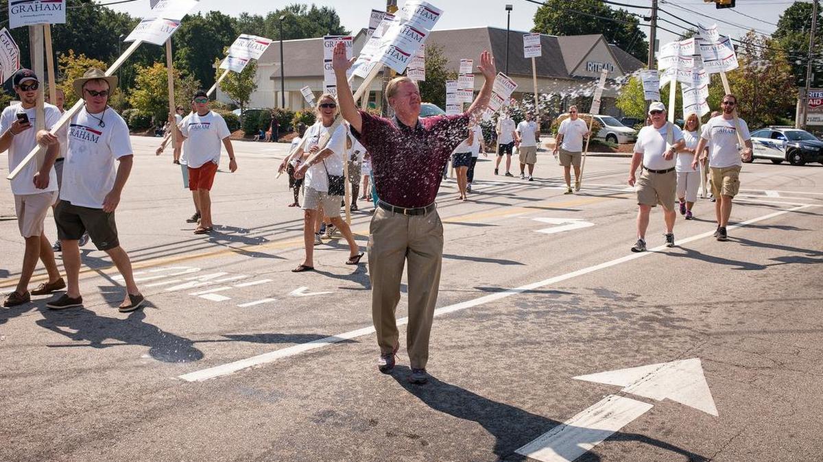 
A parade viewer in Milford, N.H., sprays Sen. Lindsey Graham with a water gun and the GOP presidential candidate playfully soaks it in.
