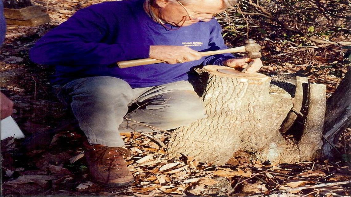 
Sid Miller, chairman of the South Carolina/North Carolina Joint Boundary Commission, sets a disk on brushy ridge for "ridge line" resurvey of South Carolina-North Carolina border above Greenville County in 2001. 

