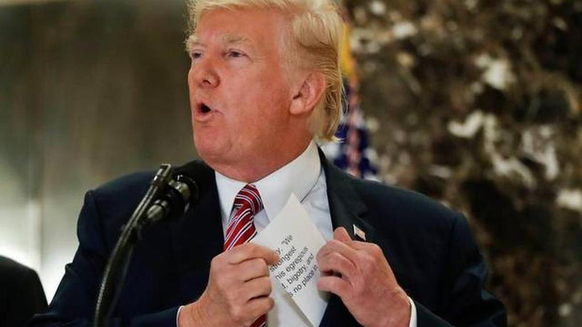President Donald Trump reaches into his suit jacket to read a quote he made on Saturday regarding the events in Charlottesville, Va., as he speaks to the media in the lobby of Trump Tower in New York, Tuesday, Aug. 15, 2017.