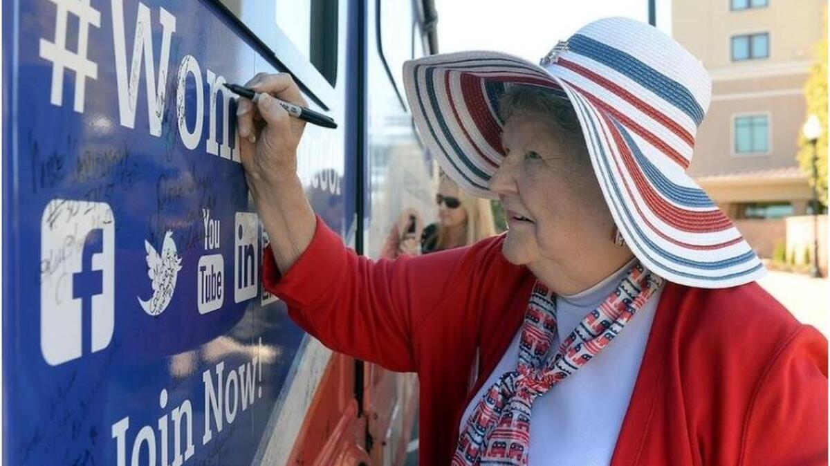 MaryAnn Riley signs “Rosie,” the name the National Federation of Republican Women gave the bus it is using to tour the nation in support of GOP candidates. The bus stopped for a brief rally at the Spartanburg Marriott.
