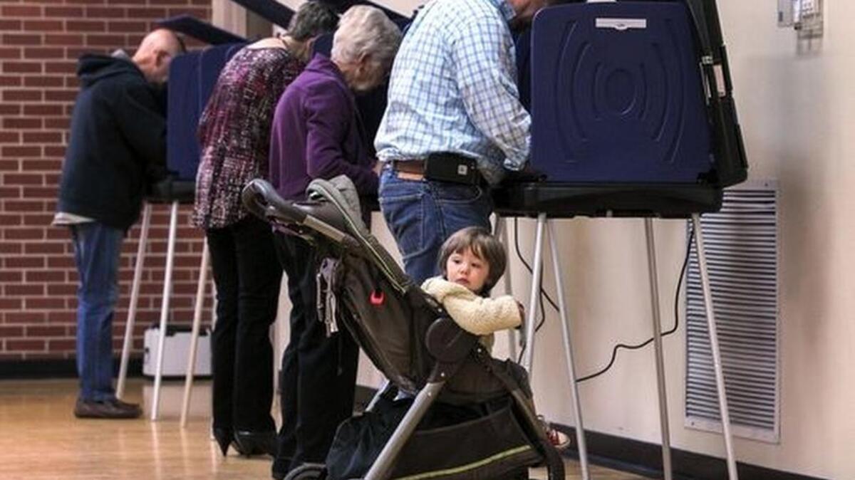 Young George Burgess looks toward the poll manager help table while his father, Darrell Burgess of Anderson, votes Tuesday at Central Presbyterian Church in Anderson.