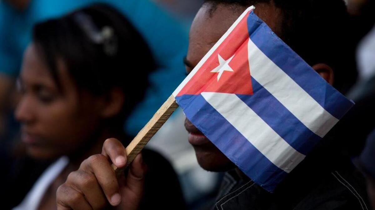 A Cuban fan uses a paper flag to shield his face from the sun during a baseball game between the Tampa Bay Rays and the Cuban national baseball team, in Havana, Cuba, last week at a game attended by President Barack Obama and Cuba's President Raul Castro.