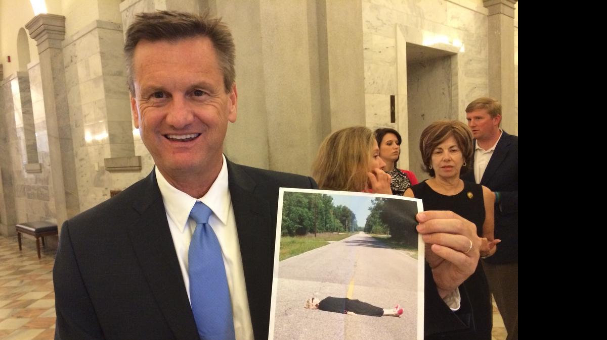 
S.C. Sen. Tom Davis, R-Beaufort, attends a press conference held by opponents of raising the gas tax. Davis is holding a picture of a woman lying in a road he says has little traffic but is slated for millions of dollars in highway improvements. 
