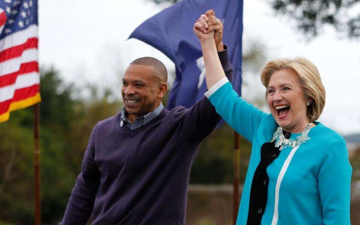 Democratic presidential candidate Hillary Rodham Clinton acknowledges the crowd at the Jenkins Orphanage in North Charleston, S.C., Saturday, Nov. 21, 2015, with S.C. State Sen. Marlon Kimpson during the Blue Jamboree event.