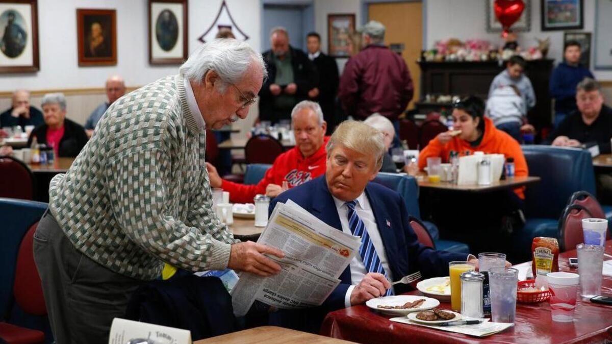 Republican presidential candidate Donald Trump looks at a newspaper with a diner at Tommy’s Country Ham House on Tuesday in Greenville.