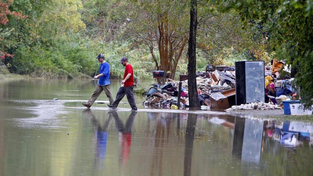 Ricky Spitz and Riley Maxwell walk through flood waters on Timberlane Drive in Columbia in the wake of the October.