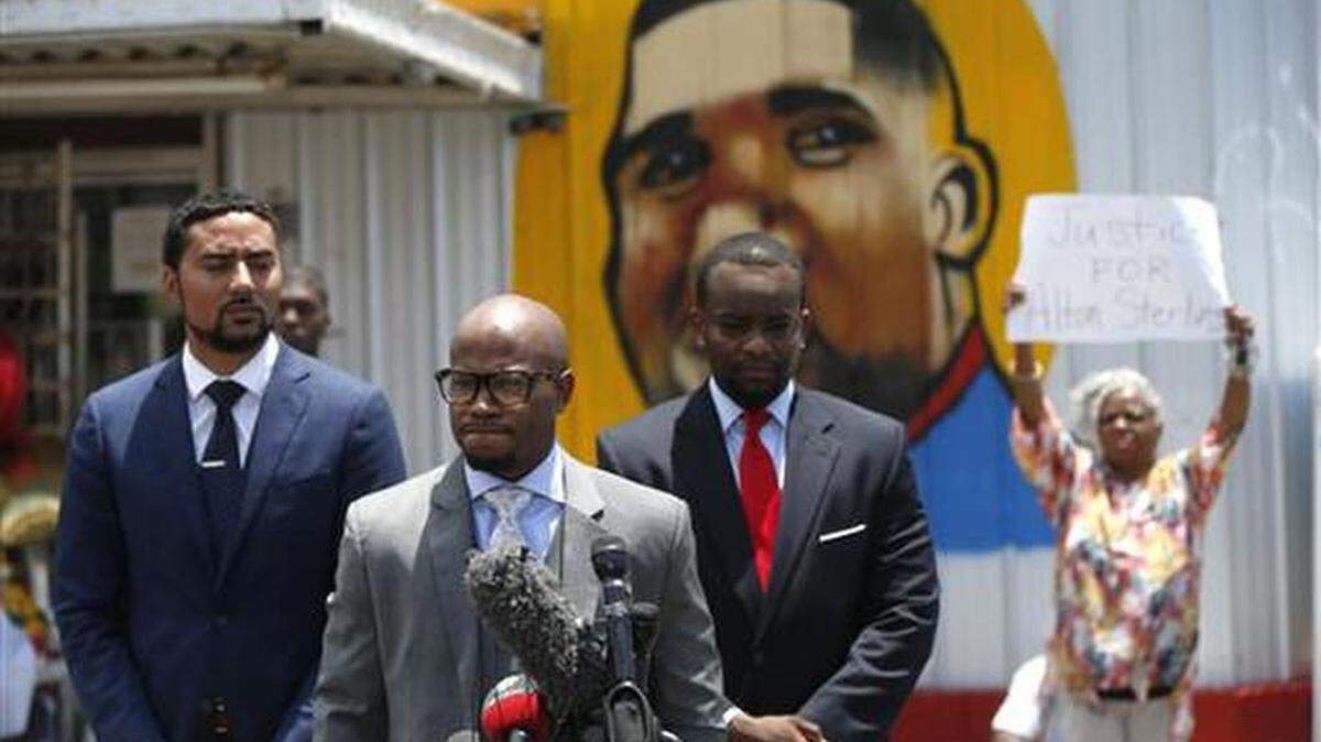 Attorneys Justin Bamberg, left, L. Chris Stewart, and Dale Glover, right, representing Quinyetta McMillon and her son Cameron Sterling, speak in front of the Triple S Food Mart in Baton Rouge, La., Thursday, July 7, 2016. Cameron is the son of Alton Sterling, 37, who was shot and killed outside the convenience store by Baton Rouge police, where he was selling CDs.