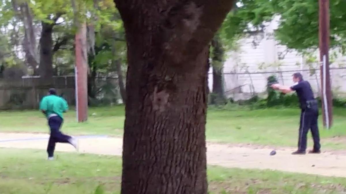 In this April 4, 2015, frame from video provided by Attorney L. Chris Stewart representing the family of Walter Lamer Scott, Scott runs away from city patrolman Michael Thomas Slager, right, in North Charleston, S.C. Slager was charged with murder on Tuesday, April 7, hours after law enforcement officials viewed the dramatic video that appears to show him shooting a fleeing Scott several times in the back.
