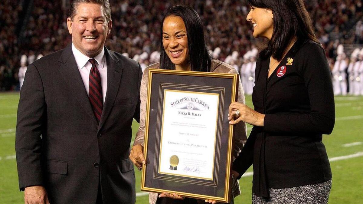 
Gov. Nikki Haley (right) gives the Order of The Palmetto to University of South Carolina women's basketball coach Dawn Staley at a 2013 football game at Williams-Brice Stadium. They are joined by Athletic Director Ray Tanner.
