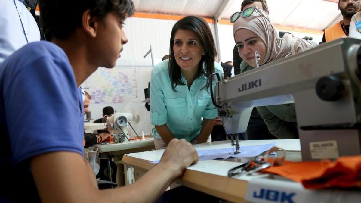U.S. Ambassador to the United Nations Nikki Haley, center, talks to a Syrian refugee who is learning how to sew clothes in a program run by the Norwegian Refugee Council and partially funded by the U.S, during a visit to the Zaatari Refugee Camp, Jordan, Sunday, May 21, 2017. Haley said the Trump administration wants to step up help for the millions of people displaced. Yet Nikki Haley's message is at odds with President Donald Trump's "America First" agenda, his planned budget cuts and his hardline position on admitting refugees.