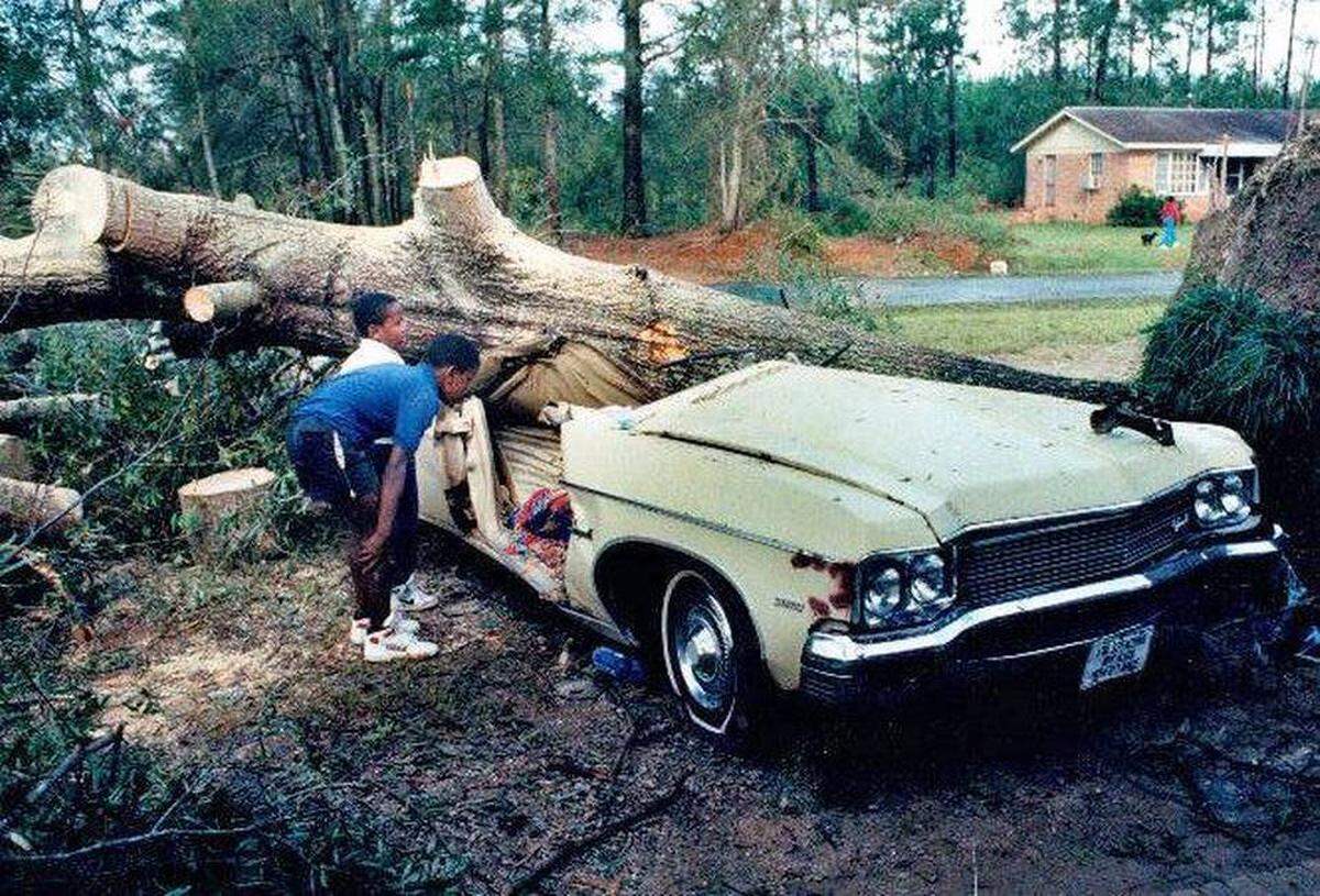 11-year-old Ricky Gilmore and 7-year-old Willie Gilmore look at a car on Sandhill Road in Eastover where Terry Capers, 30, was crushed to death by a tree during Hurricane Hugo.