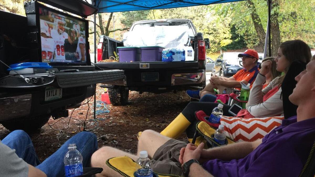Tailgating fans watch a television that is secure in a TOC Box.