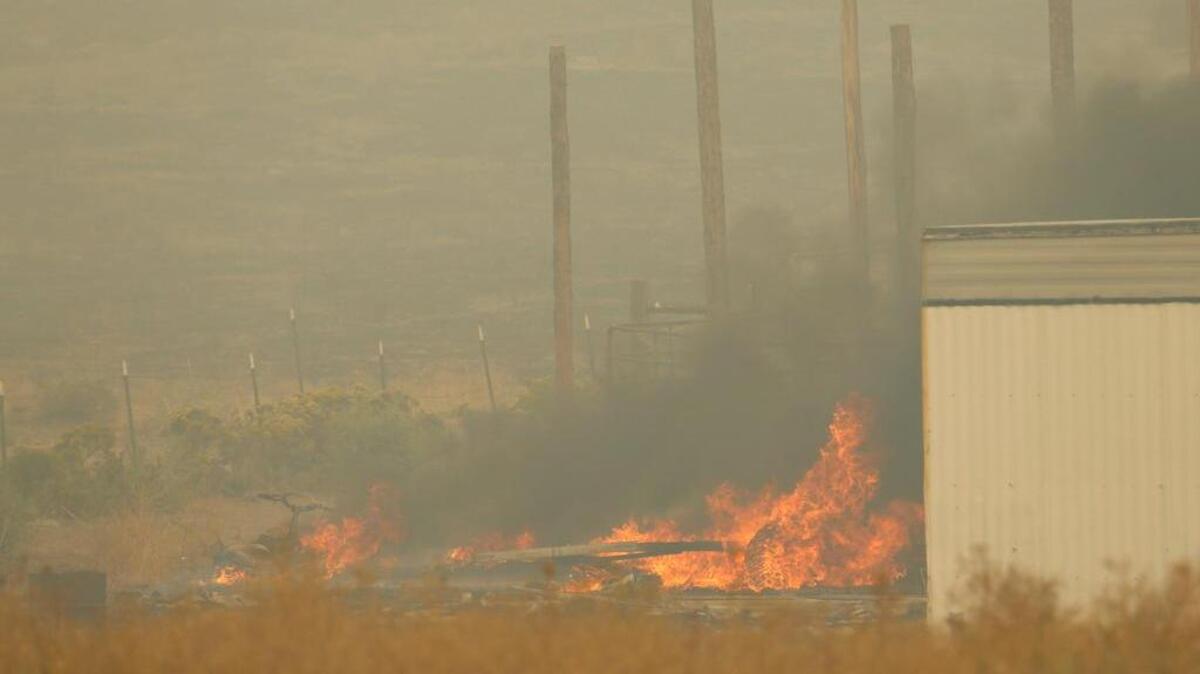
A fire burns items next to a mobile home near Omak, Wash., Wednesday, Aug. 26, 2015. The flames were extinguished in time to prevent them from spreading to the mobile home.
