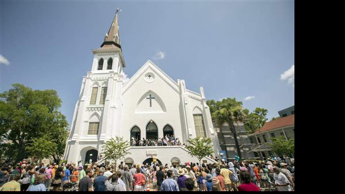 People stand outside as parishioners leave the Emanuel A.M.E. Church, Sunday, June 21, 2015, in Charleston, S.C., four days after a mass shooting at the church claimed the lives of its pastor and eight others.