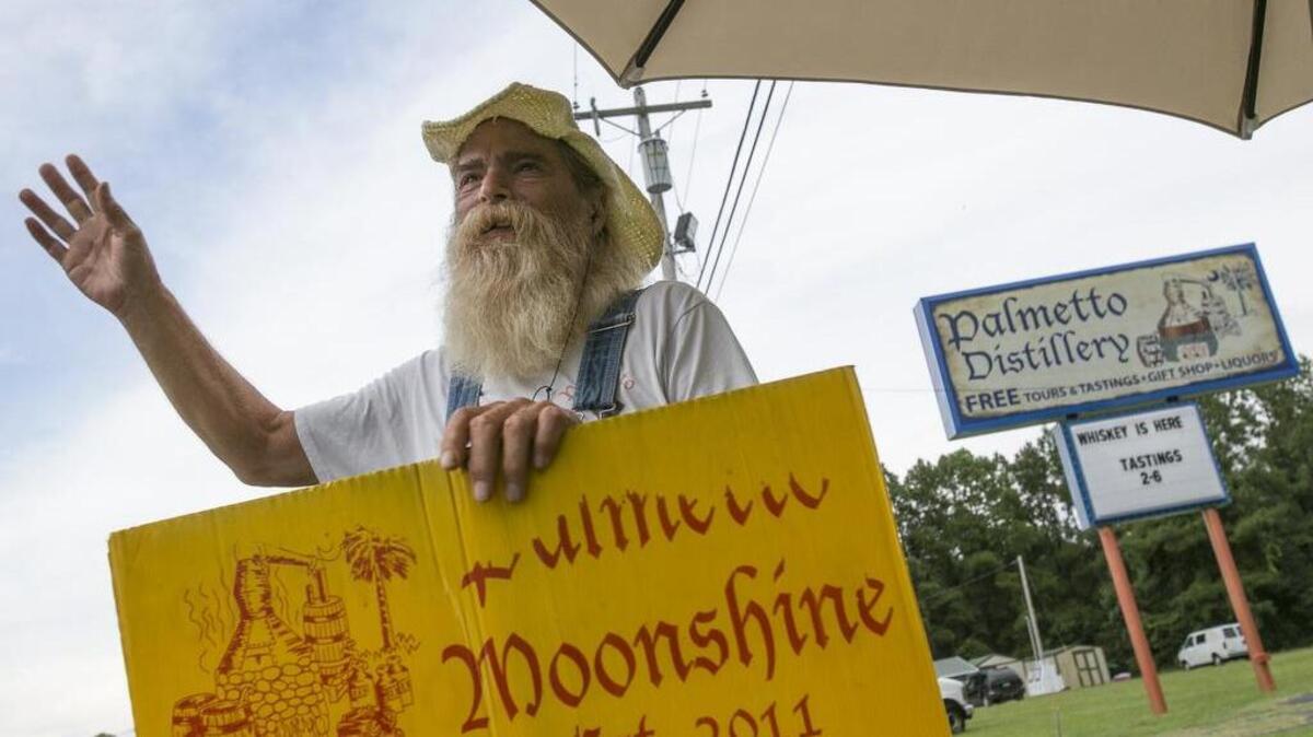 
Keith Jacob, known as "The Bootlegger" waves at passing cars in front of the Palmetto Distillery shop. Palmetto Moonshine, the state's the first legal moonshine distillery based in Anderson, gives tours and tastings at its Myrtle Beach retail store.
