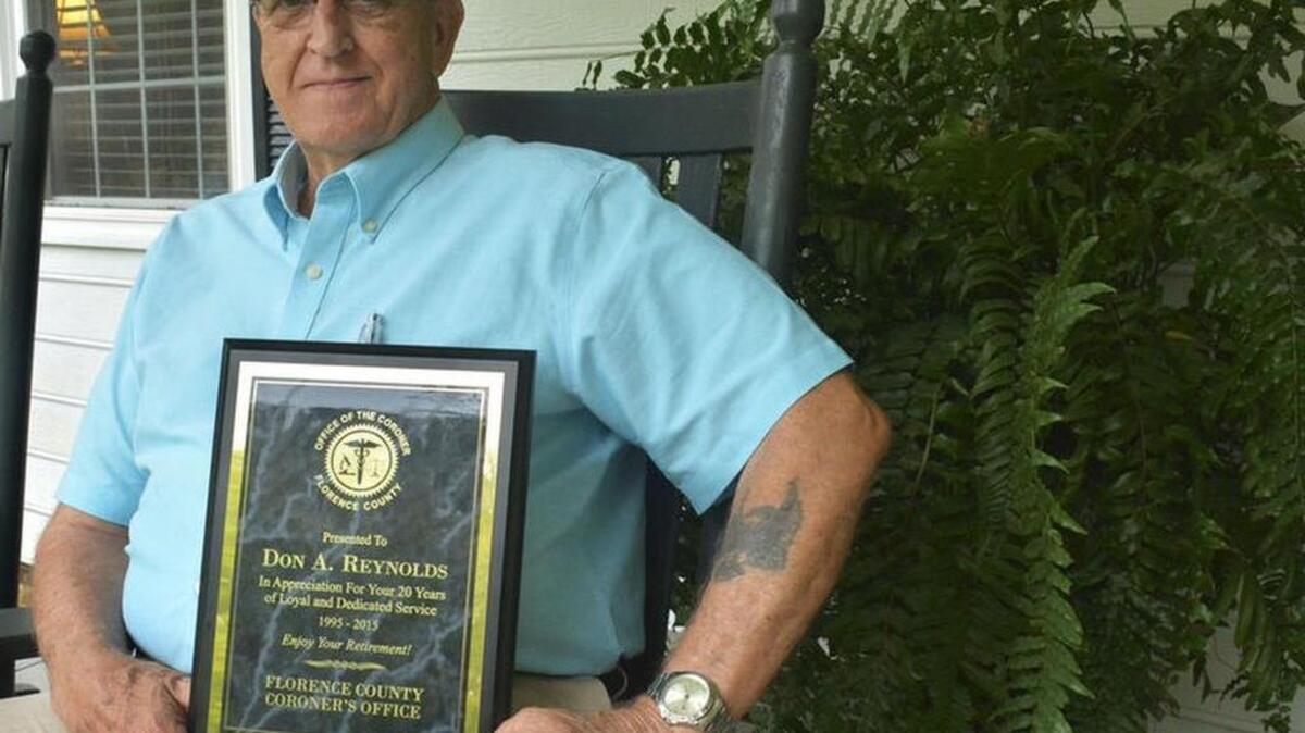 
Former Florence County Deputy Coroner Dony Reynolds sits on his front porch with a plaque signifying more than 20 years of stellar work on the job.
