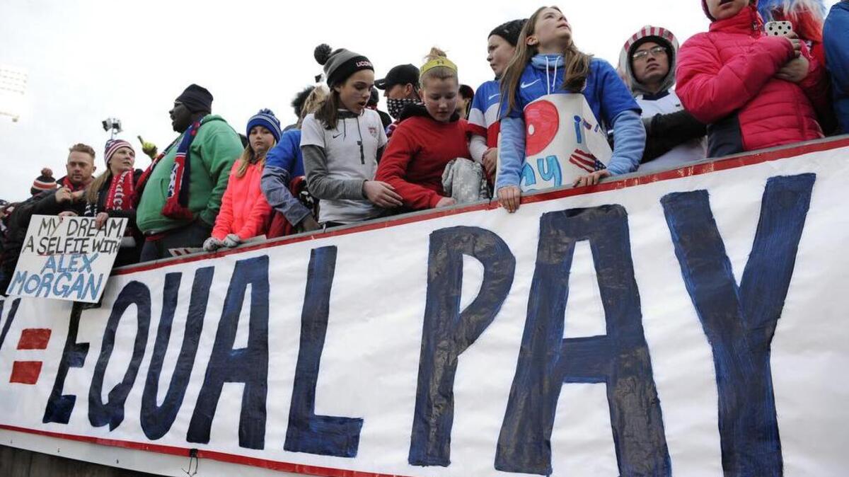 FILE photo - In this April 6, 2016, file photo, fans stand behind a large sign for equal pay for the women's soccer team during an international friendly soccer match between the United States and Colombia at Pratt & Whitney Stadium at Rentschler Field in East Hartford, Conn. The World Economic Forum's annual Global Gender Gap Report released on Oct. 25, 2016, found that the global gender pay gap will not be closed for another 170 years if current trends continue. (AP Photo/Jessica Hill, File)