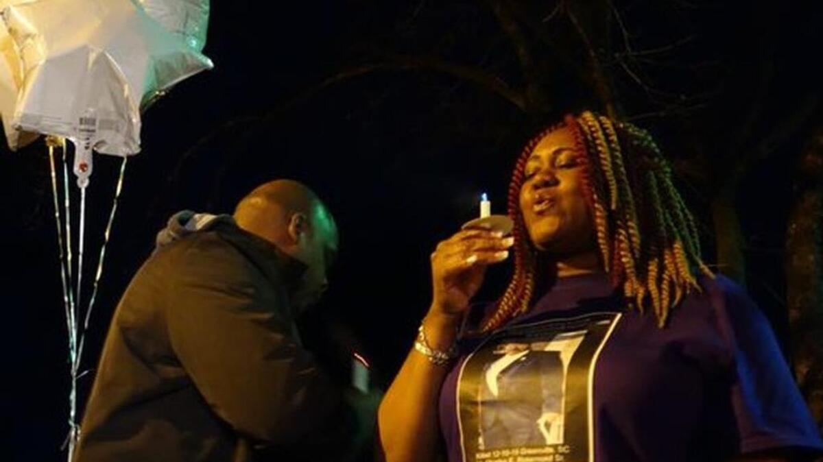 Charles Rosemond's niece, Candace Brewer, blows out a candle at a vigil at Spring Grove Apartments Saturday night.