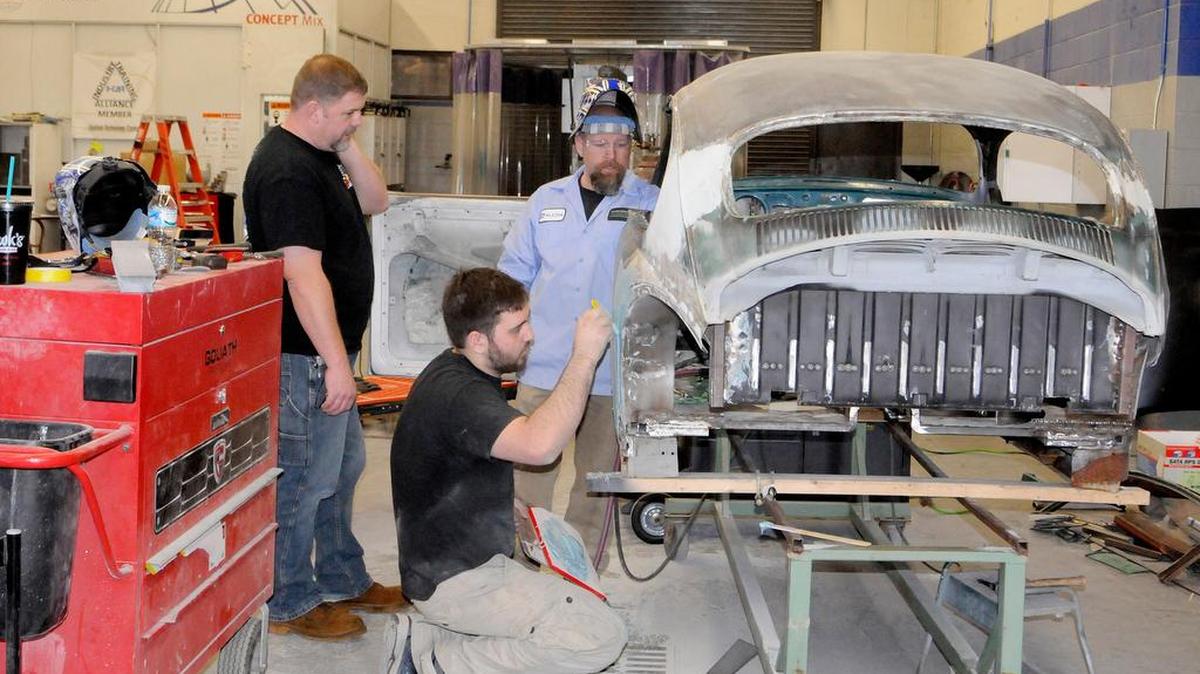 Applied Technology Center automotive instructors Gil Valk, left, and Mark Dellinger and Brian Slade, an advisory board member, discuss their work on a “rat rod” car being built by instructors and students.