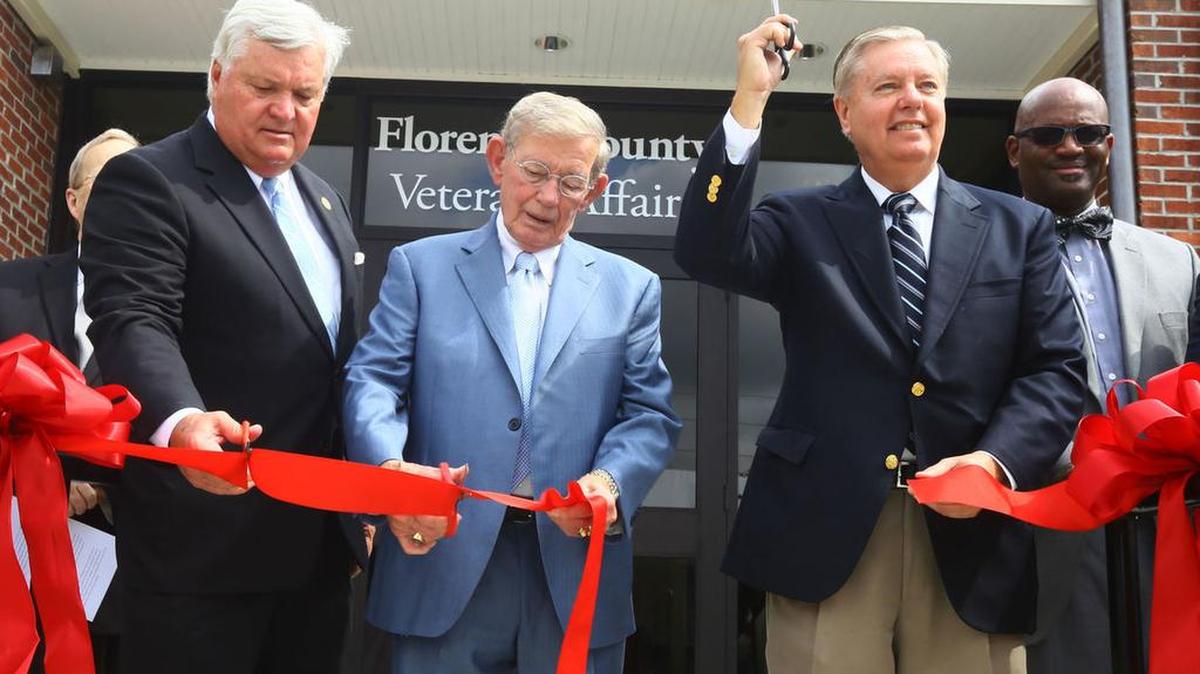 Florence County Council Chairman Kent Caudle (left), S.C. Senate President Pro-tempore Hugh K. Leatherman Sr. (center) and U.S. Sen. Lindsey Graham cut the ribbon during the grand opening ceremony of Florence County’s new V.A. Administration building on National Cemetery Road Monday.