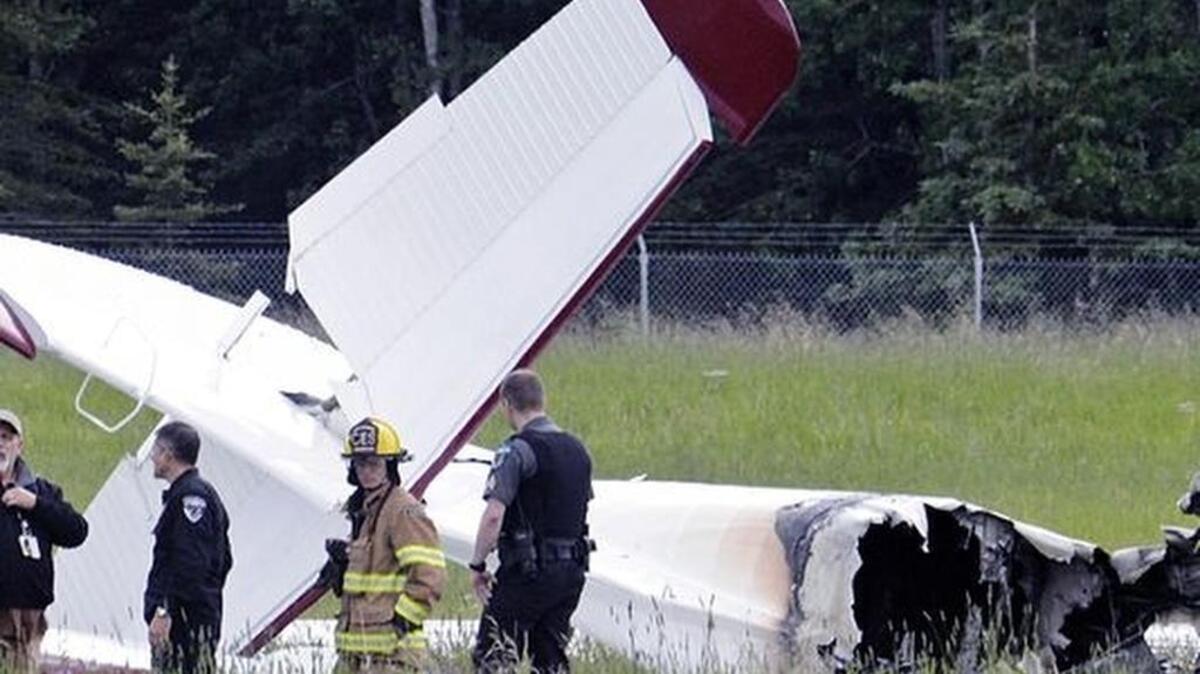 Police and emergency personnel stand near the remains of a fixed-wing aircraft that was engulfed in flames July 7, 2013, at the Soldotna Airport in Soldotna, Alaska.