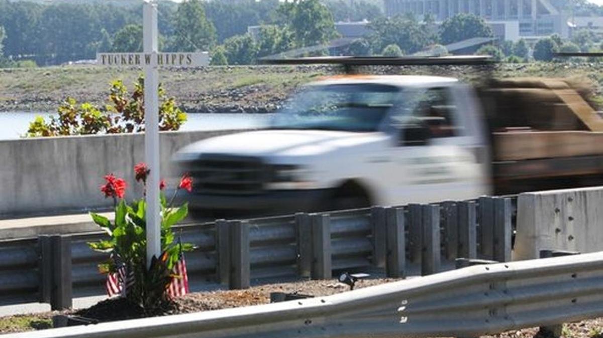 A truck drives past a cross standing in remembrance of Tucker Hipps on the S.C. 93 bridge Wednesday. Clemson's Memorial Stadium is in the background.