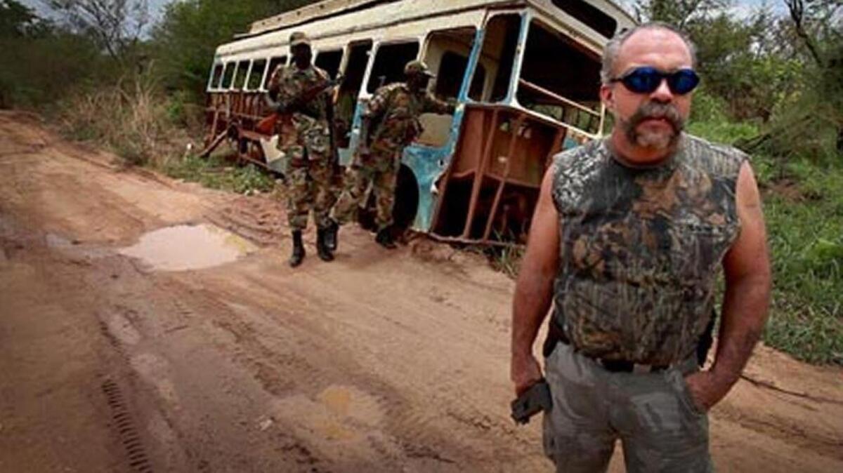 Sam Childers in front of remnants of war on the road to Juba, Africa.