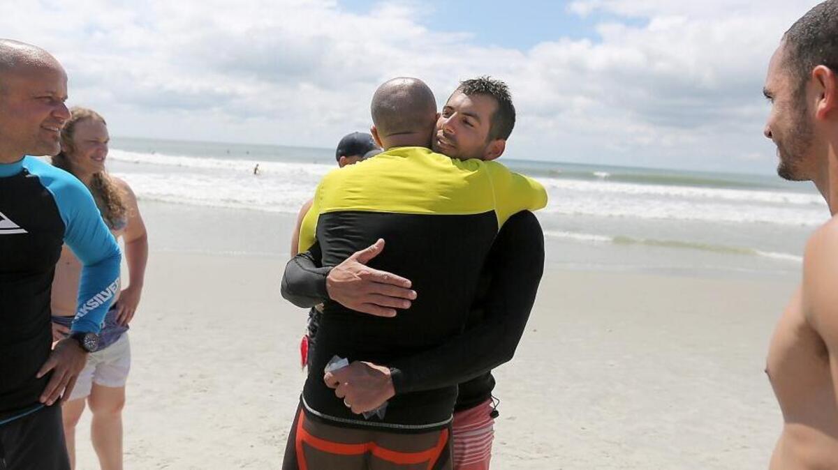 Alon Shilo (center) is embraced by other surfers after helping to rescue a man at 65th Avenue North on Tuesday, June 7, 2016. Shilo said he was paddle boarding and noticed an empty board floating near him. He said he and others surfing found Mark Allison and loaded him on the paddle board, got him to the beach and began CPR. Police on the scene said Allison was breathing and responsive as he was transported to the hospital.
