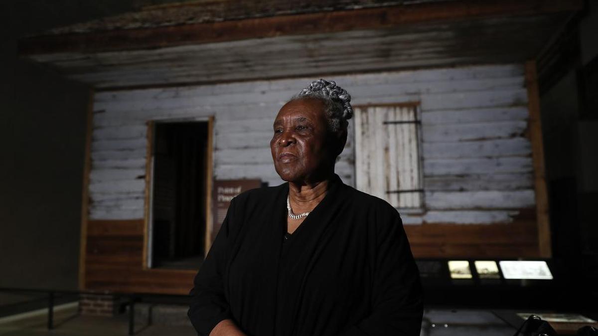 Isabell Meggett Lucas, 87, stands in front of a slave cabin at the National Museum of African American History in Washington on Tuesday. Lucas was born in the two-room wood cabin that dates to the 1850s. It is believed to be one of the oldest preserved slave cabins in the U.S.
