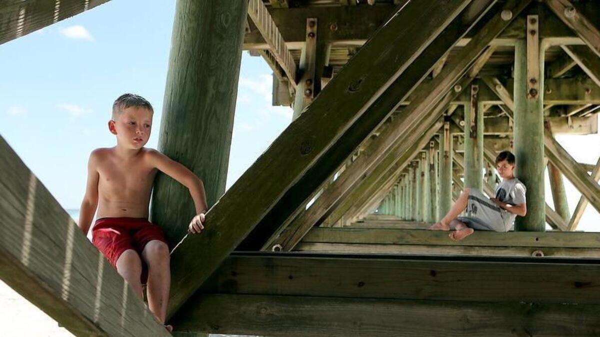 Brothers Michael Edwards (left) and Aaron Edwards find shade beneath the 2nd Avenue Pier as Myrtle Beach temperatures top 100 degrees on Friday. The Edwards family is vacationing from Winston-Salem, N.C.