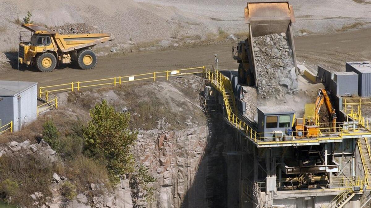 Massive trucks line up to dump blasted chunks of granite into a crusher in the Vulcan Materials quarry in Columbia.