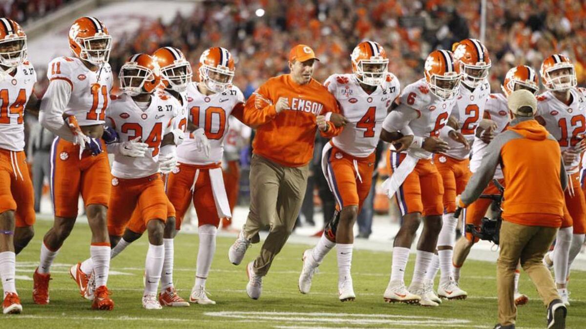 Clemson head coach Dabo Swinney connects arms with his team before January’s National Championship game.