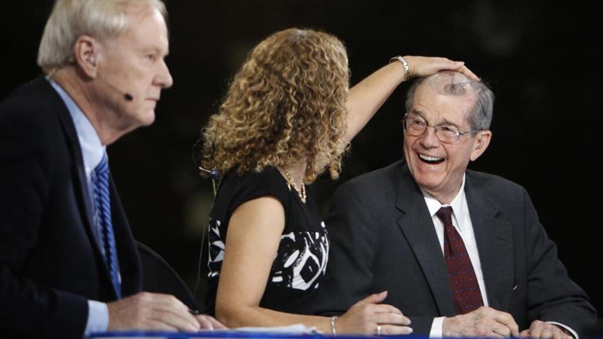 Chris Matthews waits to go live with his show “Hardball” as guest U.S. Rep. Debbie Wasserman Schultz fixes Don Fowler’s hair. Fowler was national chairman of the Democratic National Committee from 1995 to 1997.