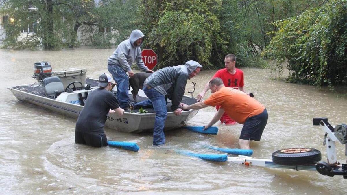 
John Wienges, from left, Bruce Fleming, Steven Smith, and Phil Lenski, help rescue Craig Smith and his dog, Hokey, from their flooded house on Timberlane Drive near Gills Creek on Sunday.
