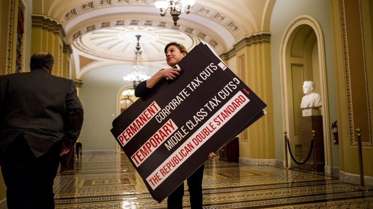 A Democratic staffer carries posters as US Senate Republicans finalized their tax bill on Friday.
