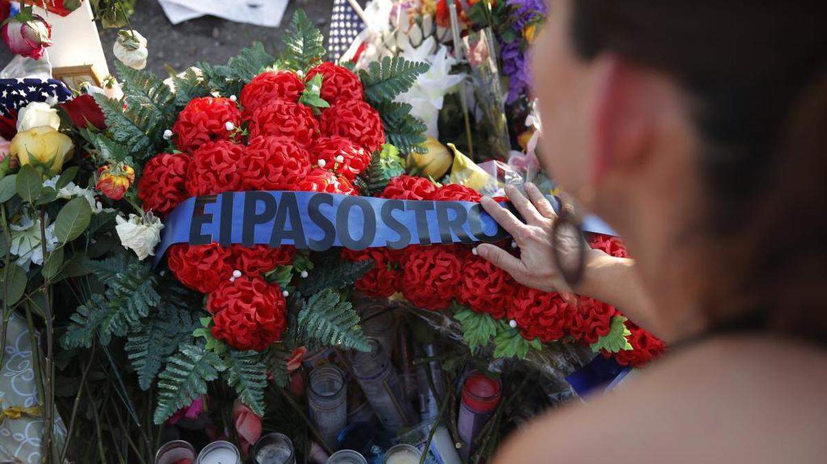 A woman leaves flowers at a makeshift memorial at the scene of a mass shooting at a shopping complex Tuesday, Aug. 6, 2019, in El Paso, Texas. (AP Photo/John Locher)