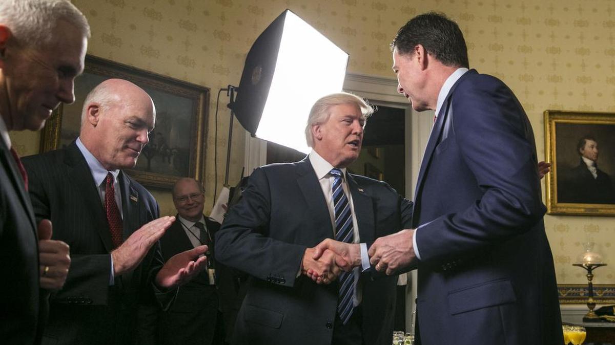 President Donald Trump and then-FBI Director James Comey shake hands during a reception at the White House on Jan 22.