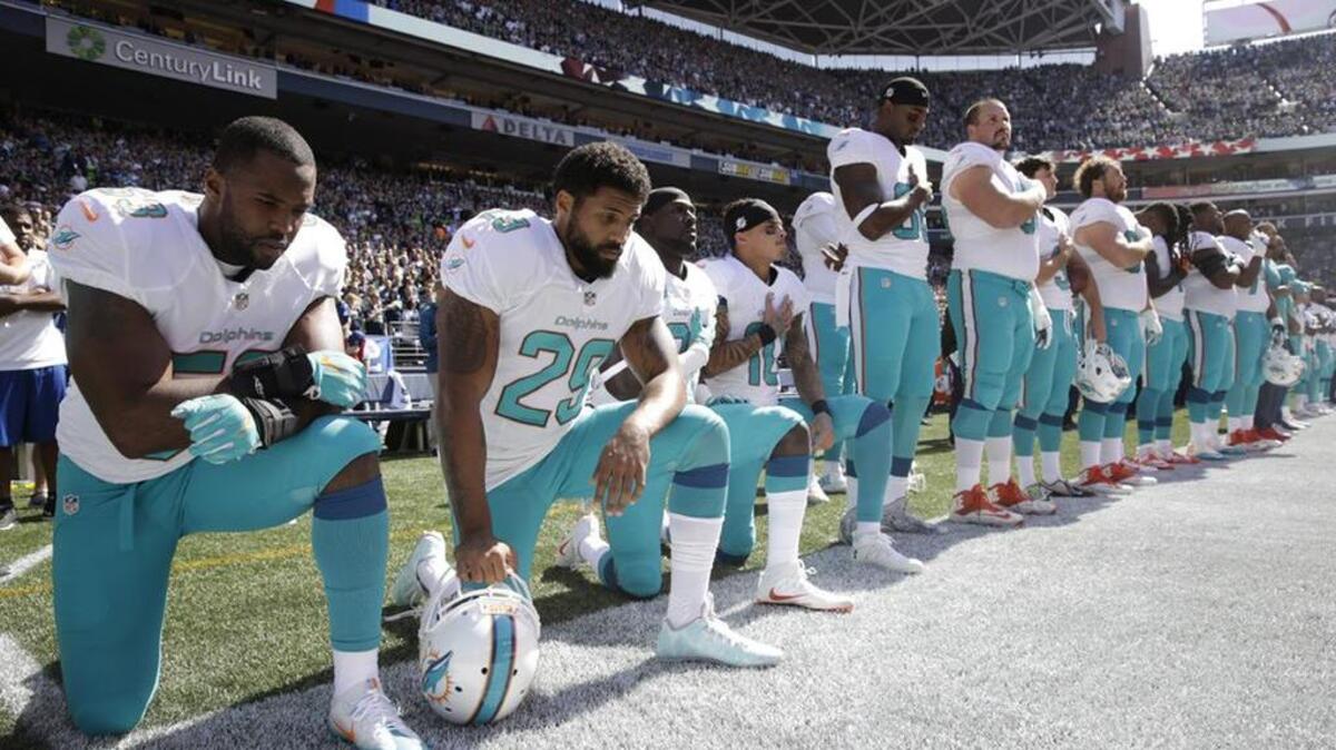 Miami Dolphins Jelani Jenkins, Arian Foster, Michael Thomas and Kenny Stills, kneel during the singing of the national anthem before a game against the Seattle Seahawks on Sept 11.