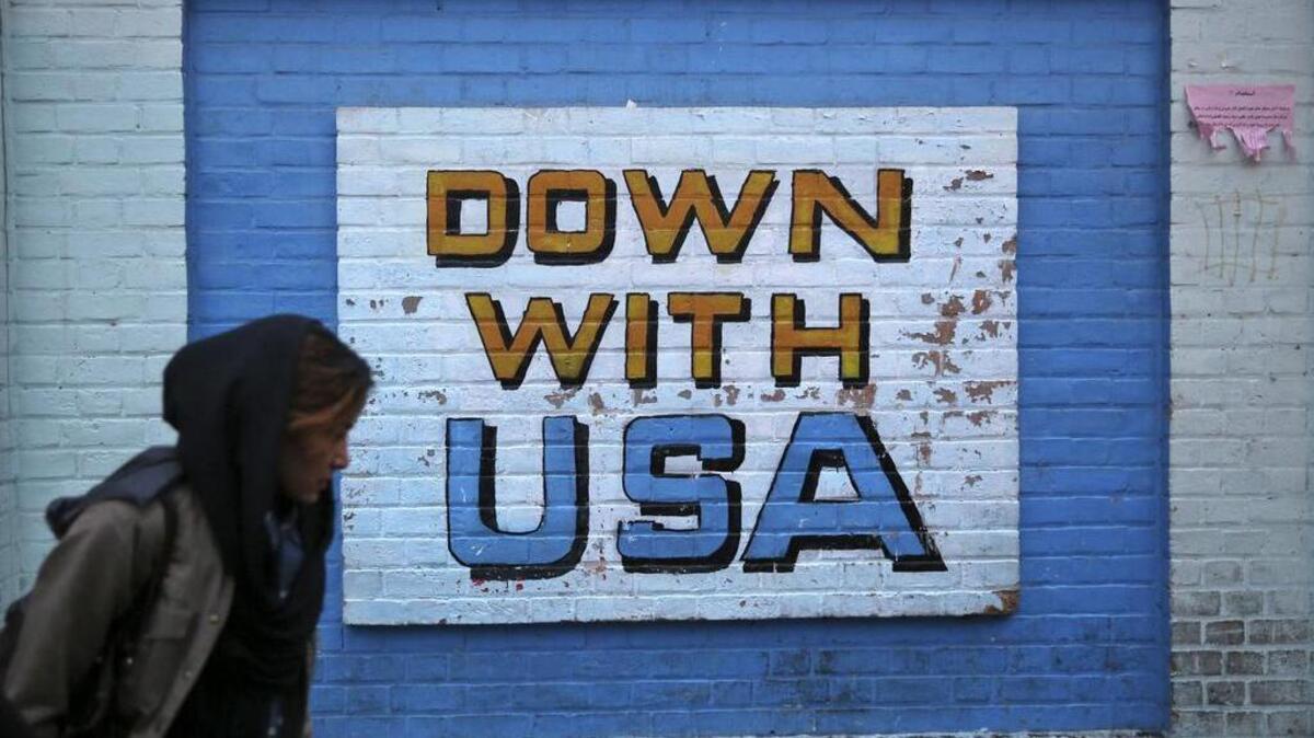 A woman walks past an anti-U.S. mural, written on the wall of the former U.S. Embassy, in Tehran, Iran.
